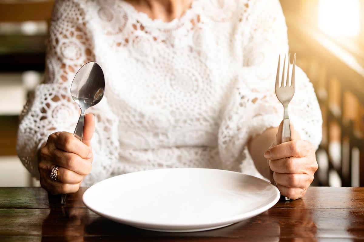 Older woman sitting at the table with an empty plate