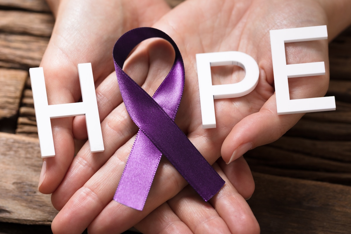 Hands holding purple ribbon for Alzheimer's Awareness Month