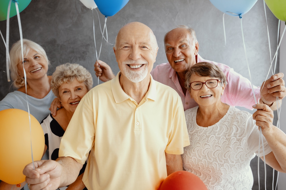 Elderly adults smiling and holding balloons