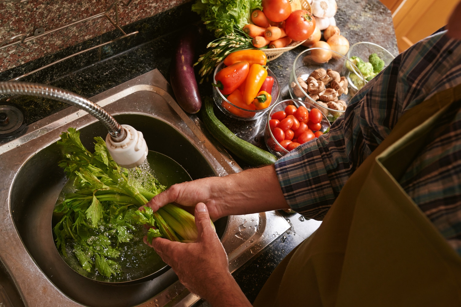 Man washing vegetables in sink