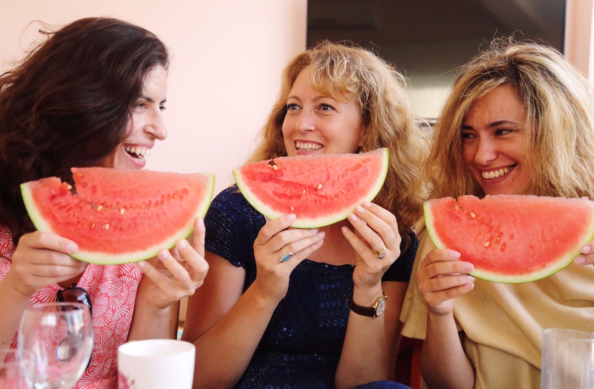 Three women eating watermelon