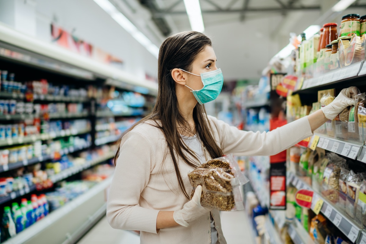 Woman wearing mask and gloves in grocery store during COVID-19 pandemic