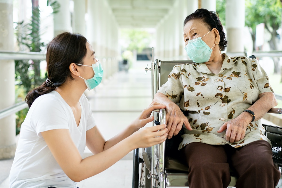 Nurse with Woman in Wheelchair both wearing masks