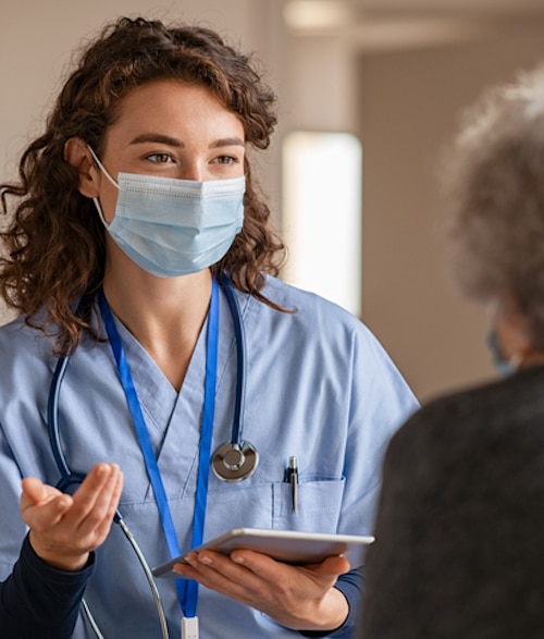 Young doctor visits senior woman with surgical mask Best Practices in Nutrition Focused Physical Exam